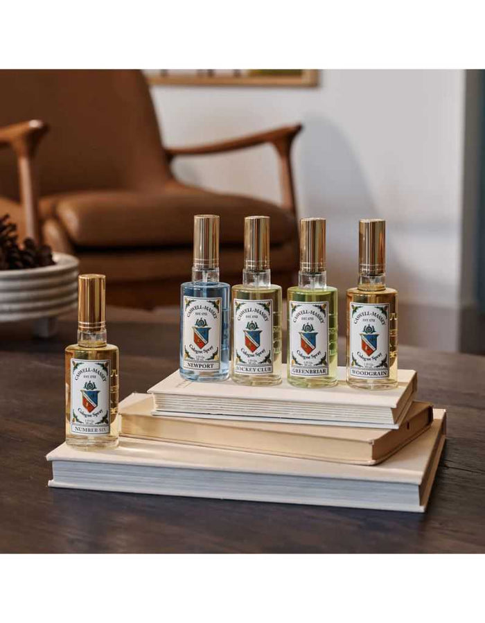 Set of four Colgate sprays with different labels, citrus woody fragrance, on books